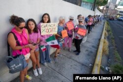 Votantes, algunos con un cartel de apoyo a la candidata presidencial de la oposición Xóchitl Gálvez, hacen fila afuera de un colegio electoral durante las elecciones generales en la Ciudad de México, el 2 de junio de 2024. (AP/Fernando Llano)