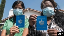 Inmigrantes cubanas muestran sus pasaportes mientras protestan frente a la agencia de la ONU para refugiados en Costa Rica. Ezequiel BECERRA / AFP