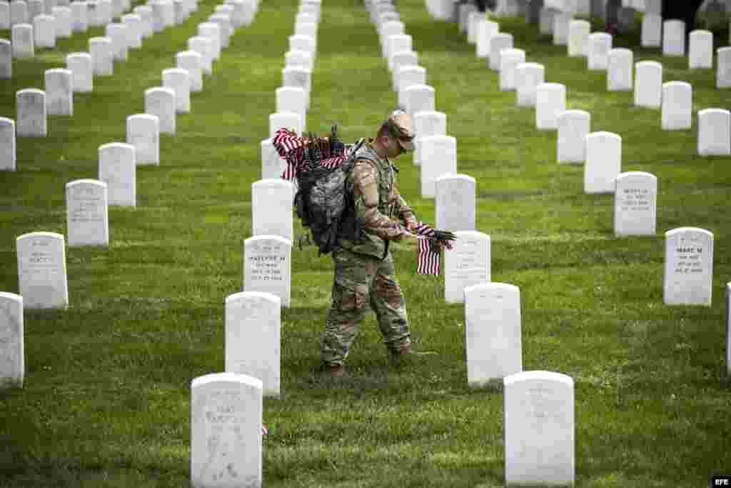 Soldados del Tercer Regimiento "La vieja guardia" de Infantería del Ejército de EEUU depositan banderas americanas en cada lápida durante una ceremonia por el Día de los caídos, en el Cementerio Nacional de Arlington, en Virginia.