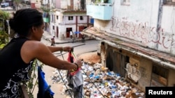 Una mujer cuelga ropa en una tendedera cerca de un montón de basura en la calle, en La Habana, Cuba, 31 de agosto de 2024. REUTERS/Norlys Perez