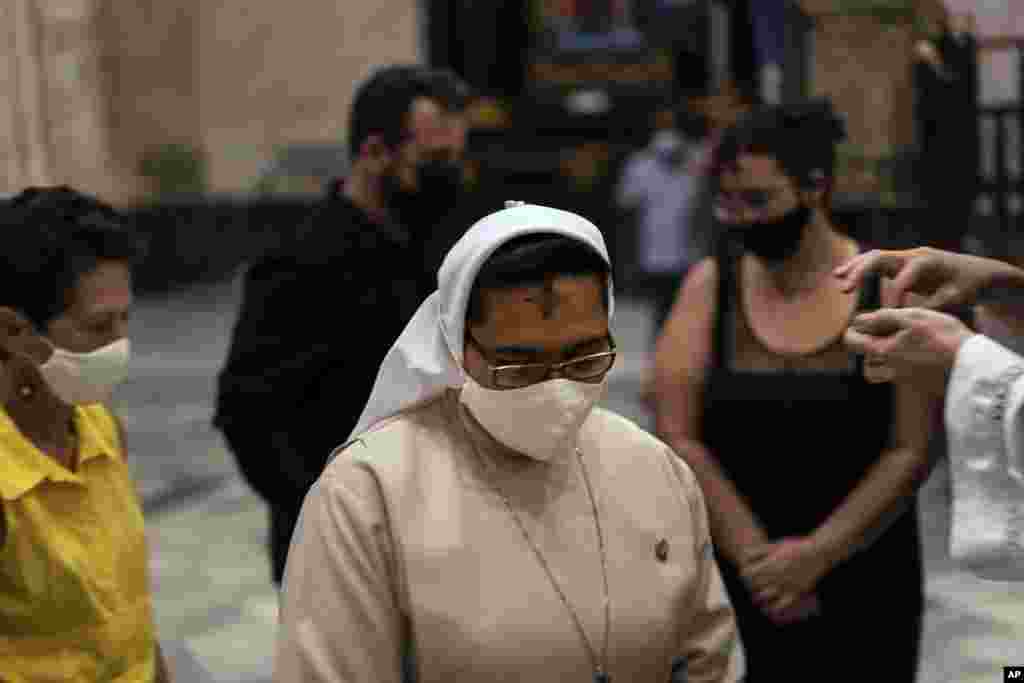 Una monja con máscara recibe la ceniza durante la Misa del Miércoles de Ceniza en La Habana, Cuba.